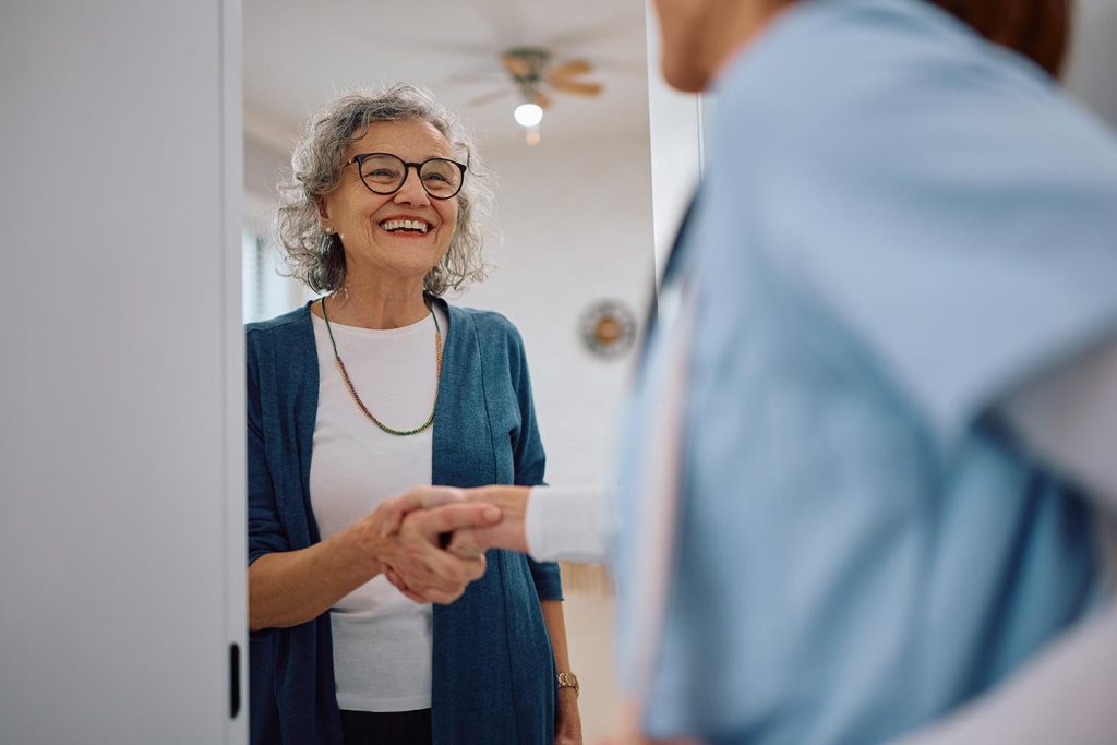 Mature woman greeting a support worker at home during supported independent living care
