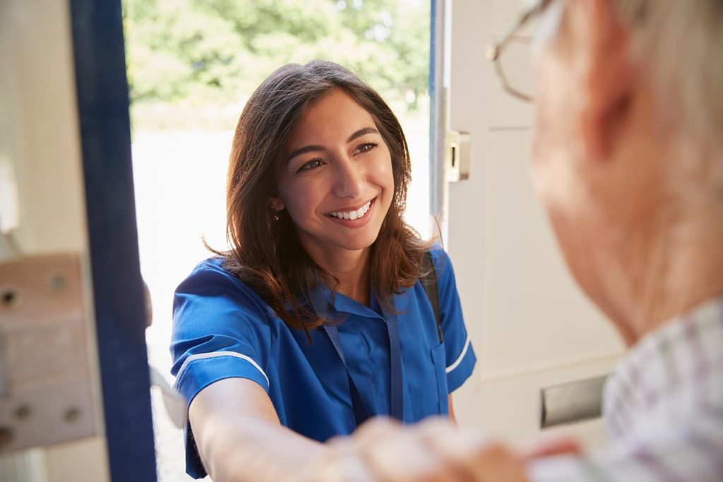 Nurse visiting a senior man at home and greeting him during a home care support visit